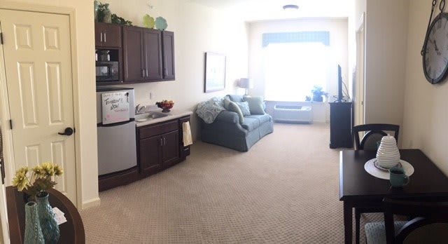 A cozy living space with a kitchenette and a sofa by a large window.