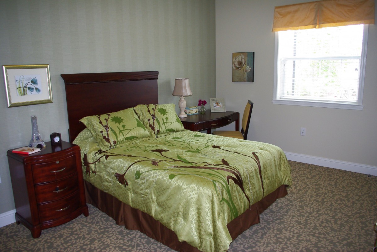 A cozy bedroom with a green-themed bedding and simple decor.