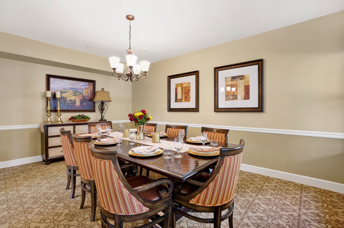 A beautifully decorated dining room with a large table, elegant chairs, artwork on the walls, and a stylish chandelier.