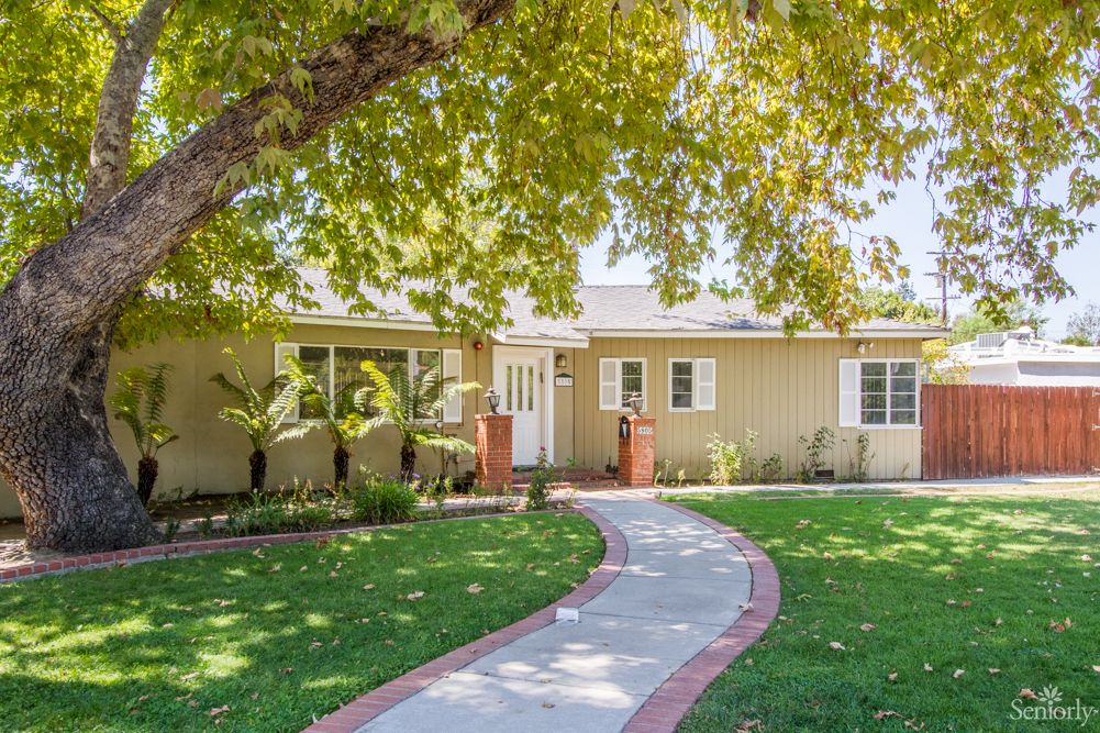 A suburban house with a neatly maintained front yard and a curved pathway leading to the entrance.