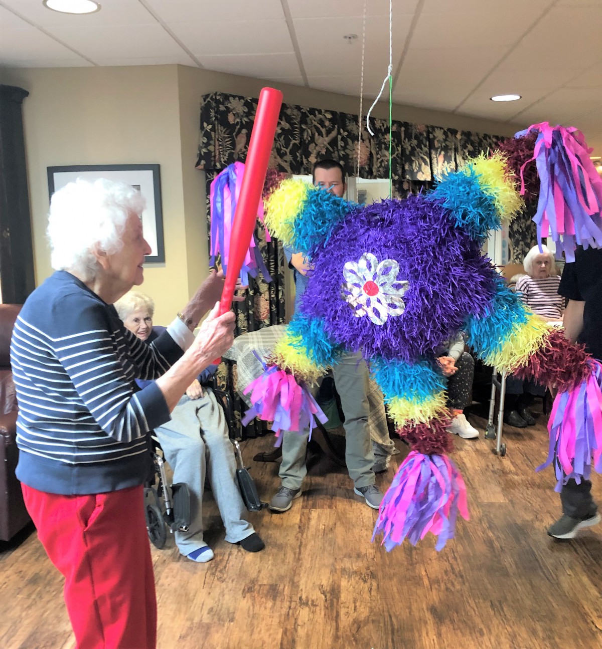 A group of seniors enjoying a piata party indoors.