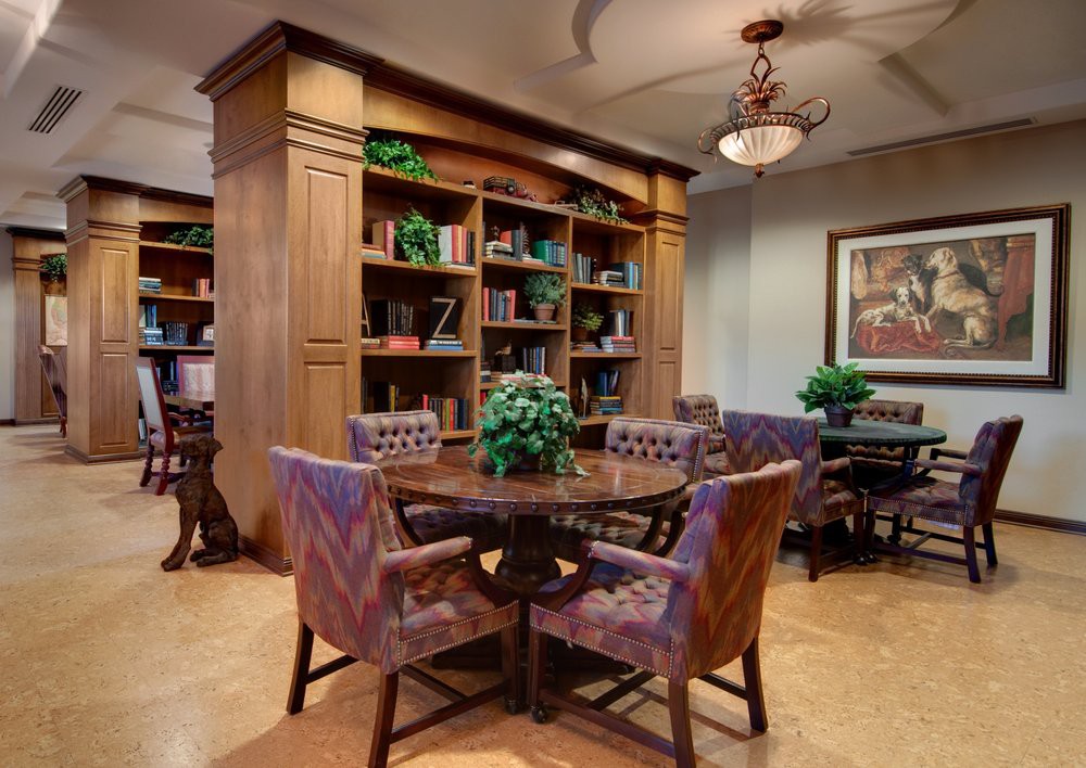 A cozy library setting with bookshelves, a round table, and upholstered chairs.