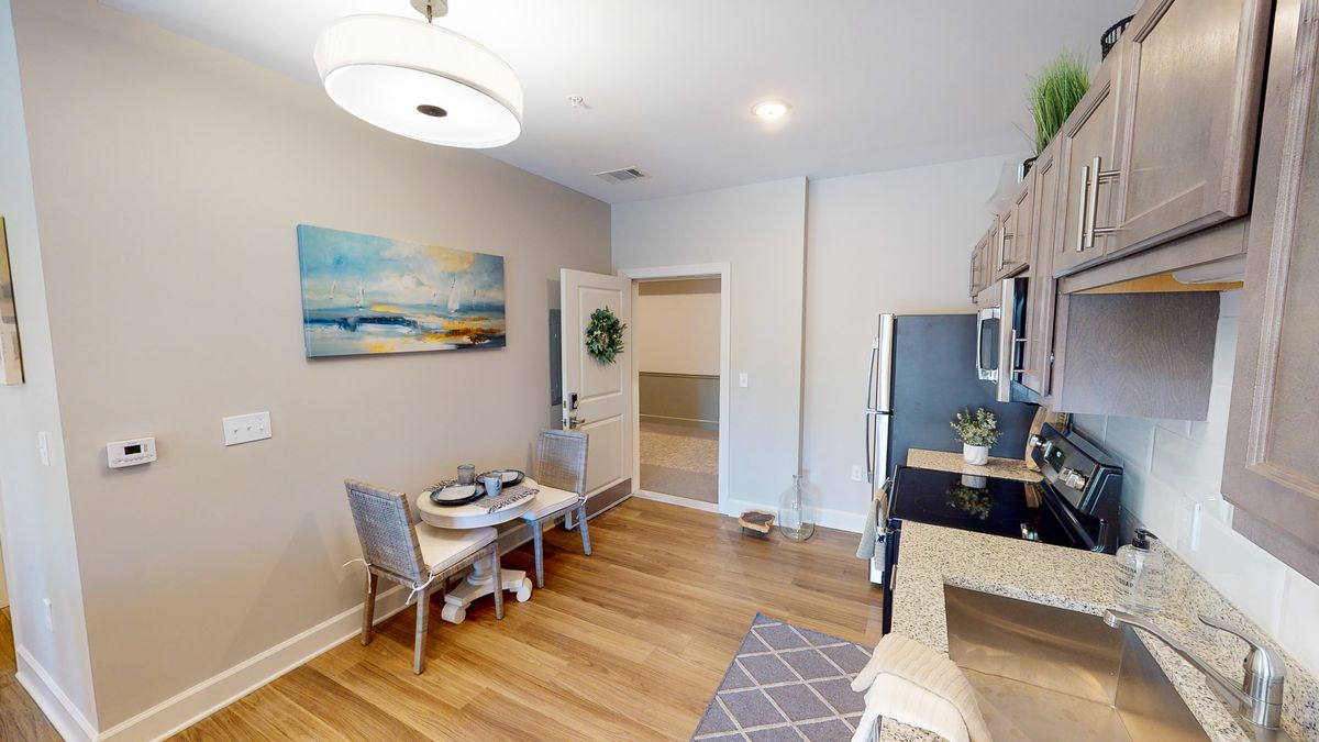 A modern kitchen with a cozy dining area, featuring a small table and chairs, stainless steel appliances, and elegant decor.