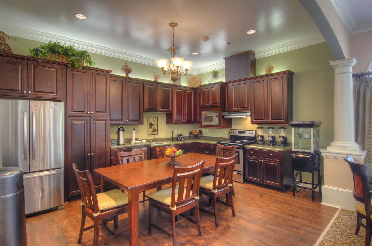 A spacious kitchen with wooden cabinetry, a dining table and chairs, and modern appliances.