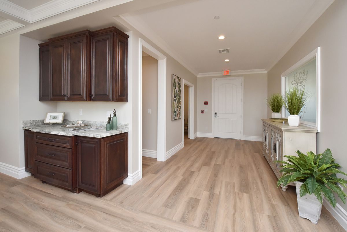 A modern hallway with wooden flooring and dark wooden cabinets.