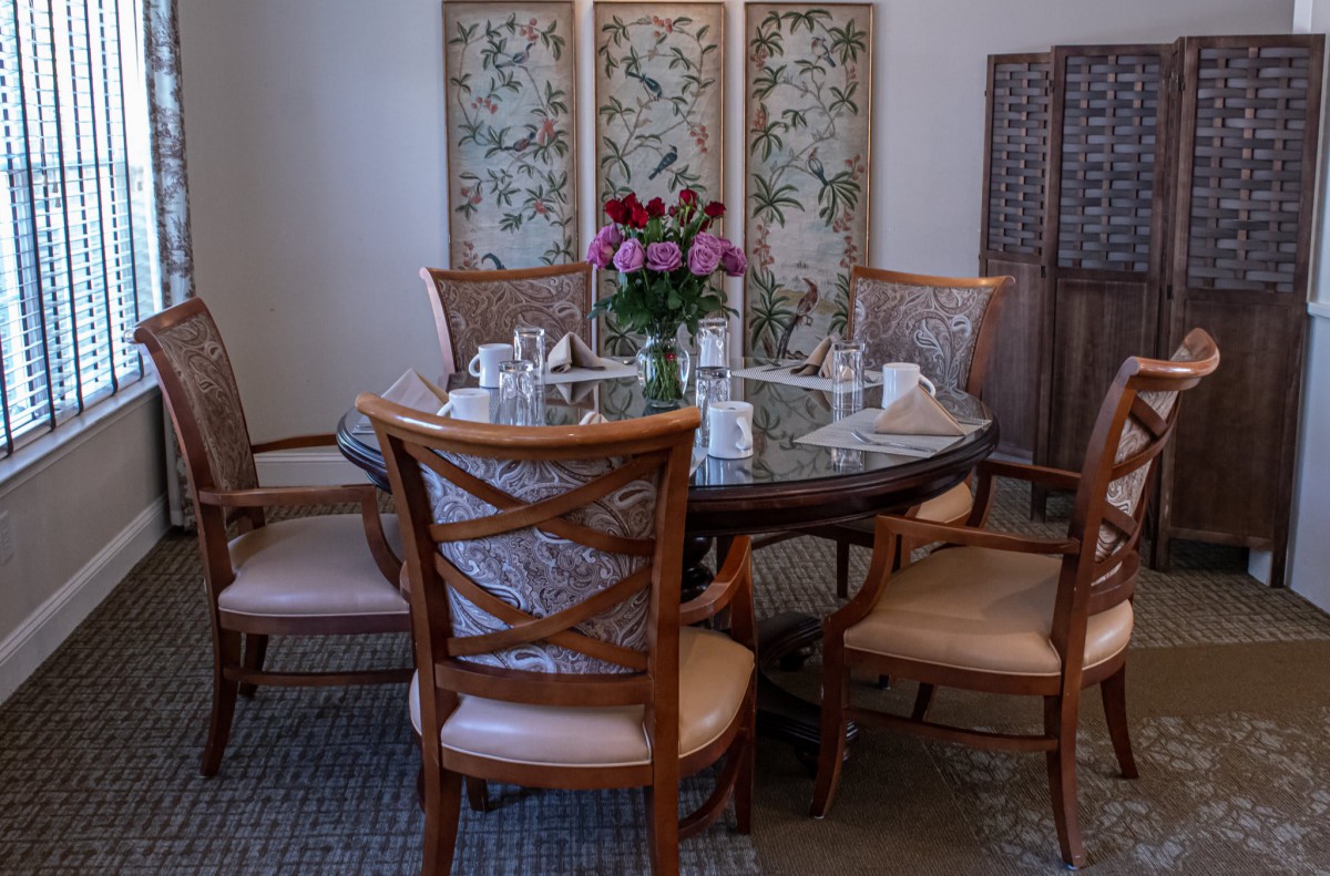 Elegant dining room setup with a flower centerpiece and decorative screen backdrop.