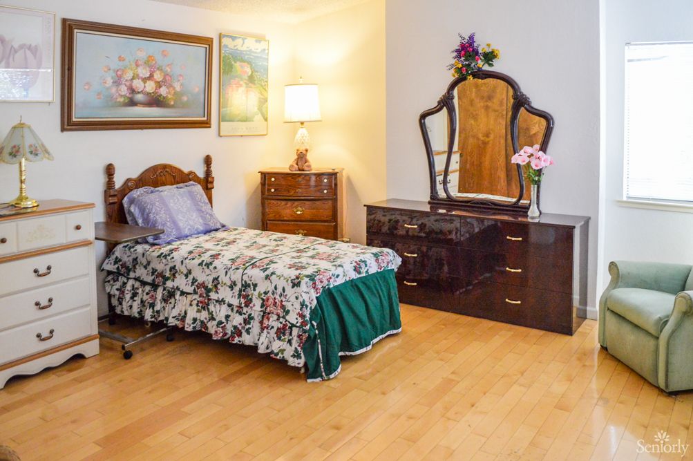 A cozy bedroom featuring traditional furnishings, including a single bed and a dresser with a mirror.