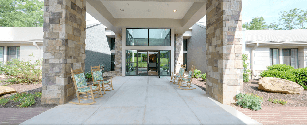 Modern building entrance with glass doors and rocking chairs.