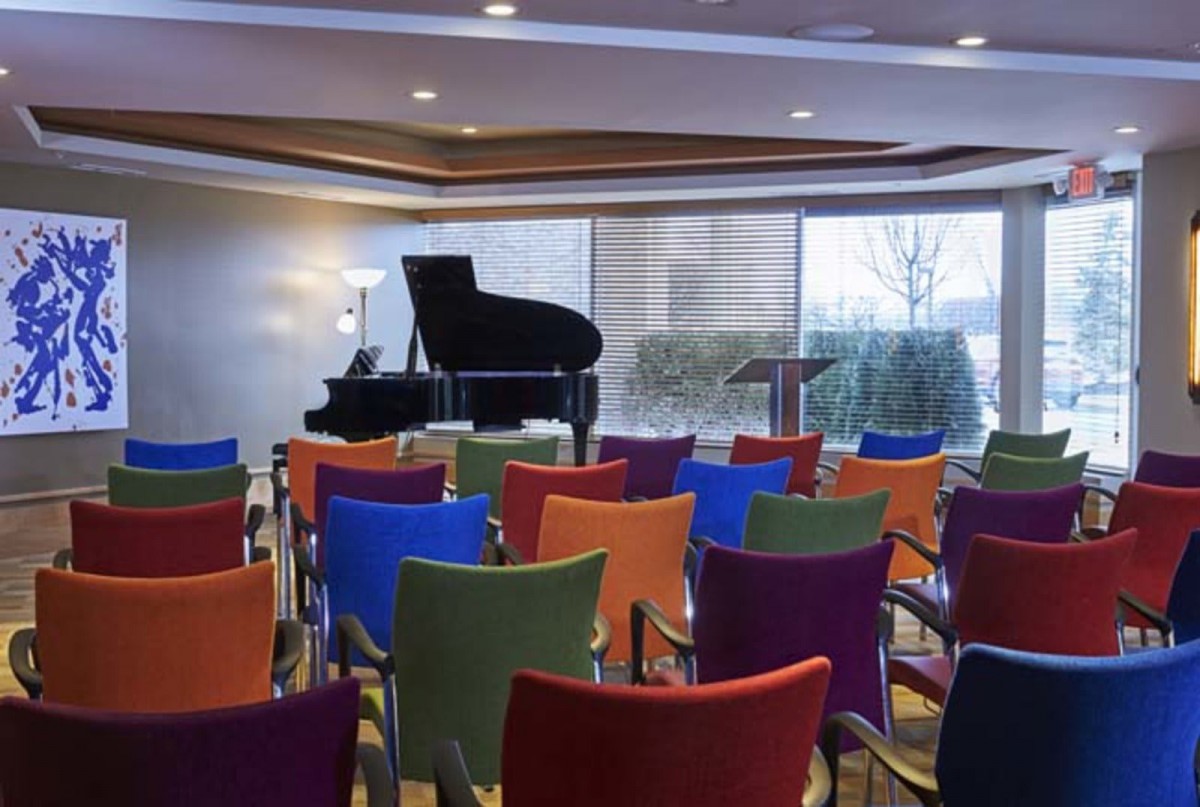 A conference room with colorful chairs arranged in front of a grand piano.