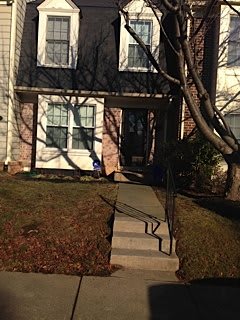 A residential house with a front yard, featuring stairs leading to the entrance.