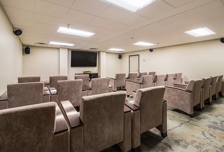 A modern conference room with multiple rows of seating and a large television.