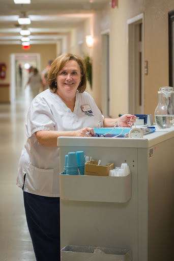 A friendly nurse smiles while attending to her duties in a hospital corridor.