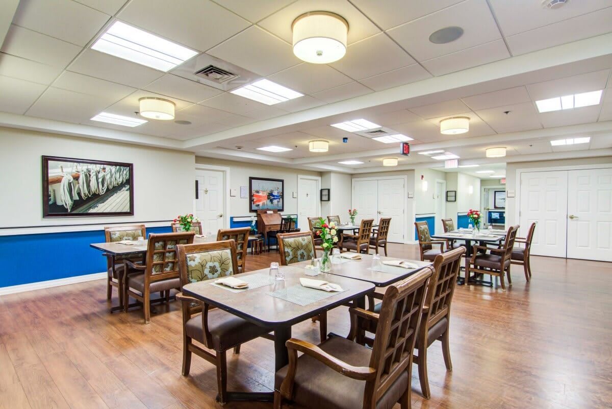 A spacious, well-lit dining area with wooden flooring and neatly arranged tables and chairs.