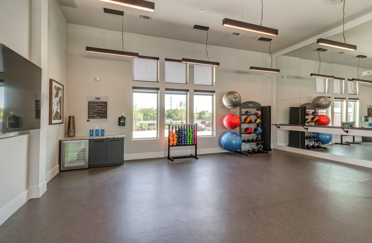 Modern gym with exercise equipment and large windows.