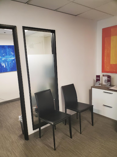A modern waiting room with black chairs and abstract artwork on the wall.