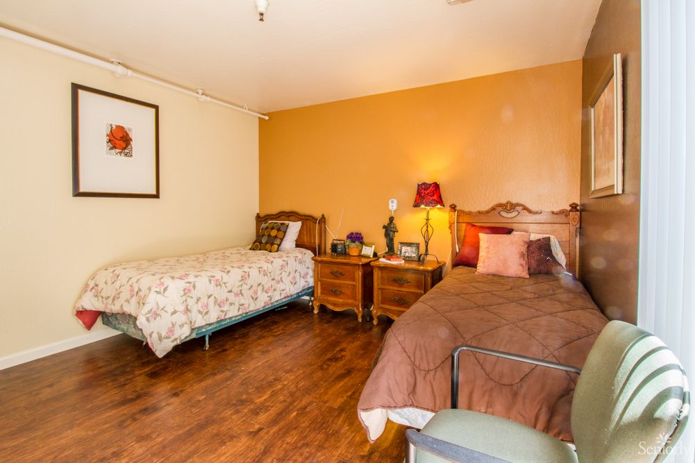 A cozy bedroom with two beds, wooden flooring, and a warm color scheme.