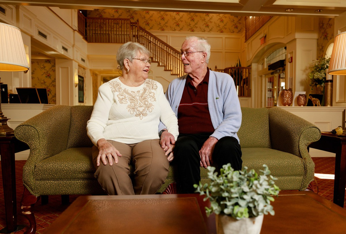 An elderly couple sitting together on a couch in a cozy living room.