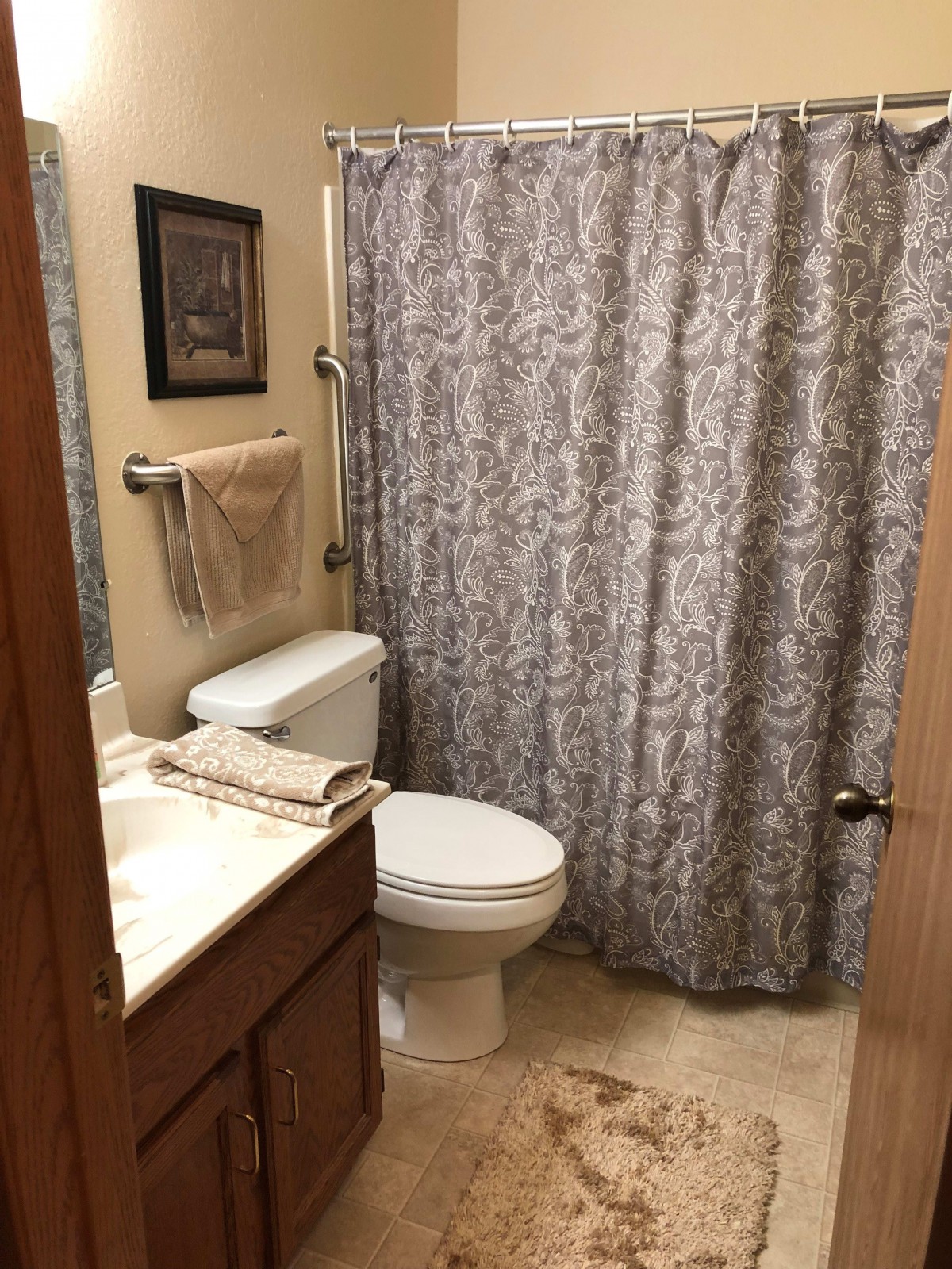A small, neatly arranged bathroom with a patterned shower curtain.