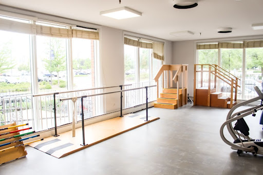 A spacious physical therapy room equipped with walking rails and stairs for rehabilitation exercises.
