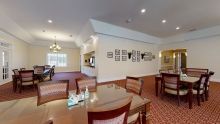 An elegant dining area with tables and chairs, featuring warm lighting and decorative wall accents.