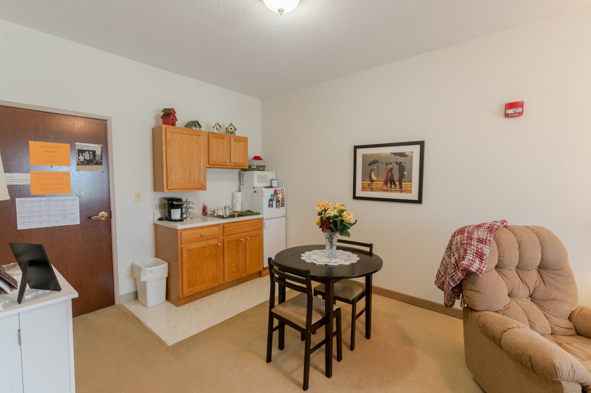 A cozy apartment interior featuring a small kitchen and dining area with a table and chairs.