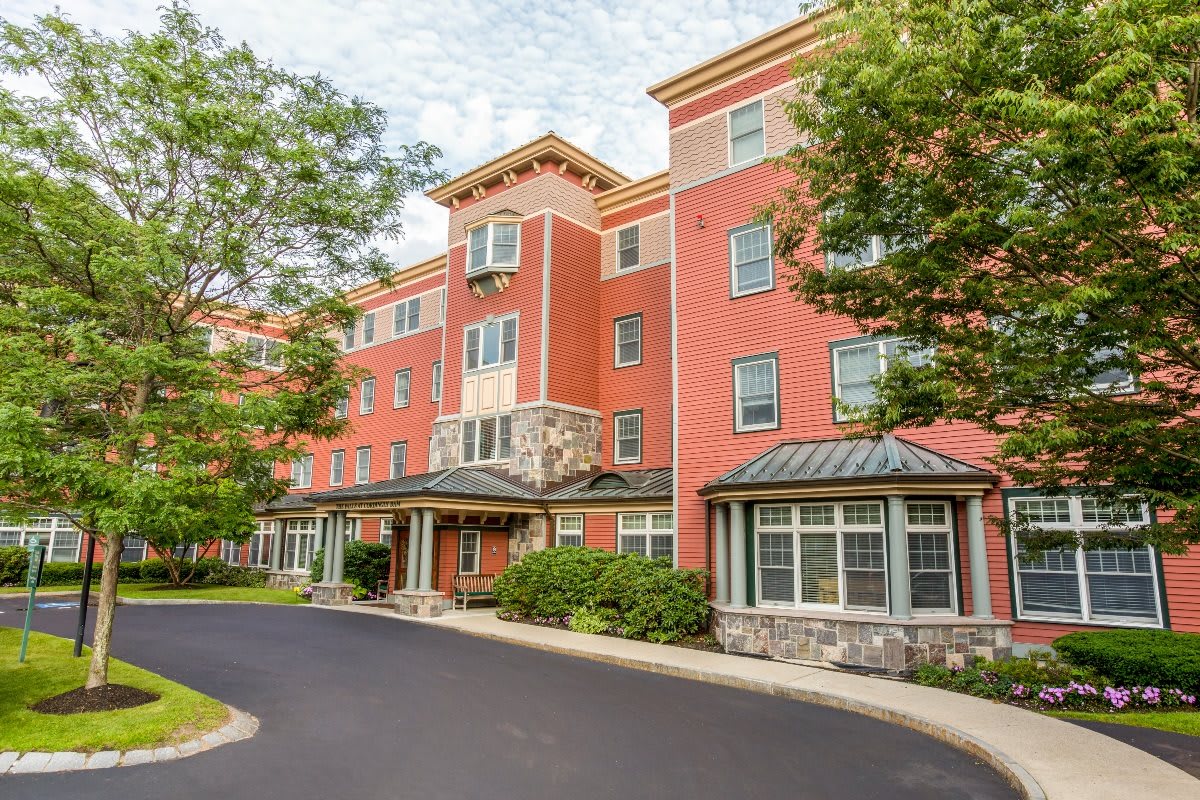 A multi-story residential building with a brick facade surrounded by greenery.