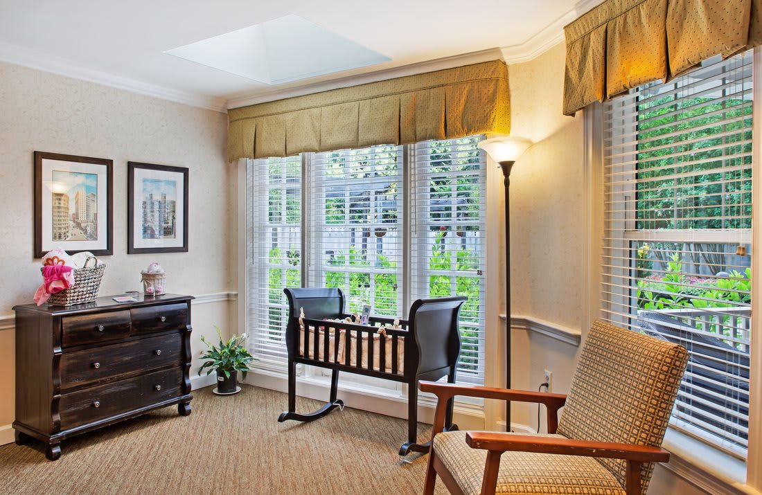 A cozy living room with a desk and chair by the window, illuminated by natural light.