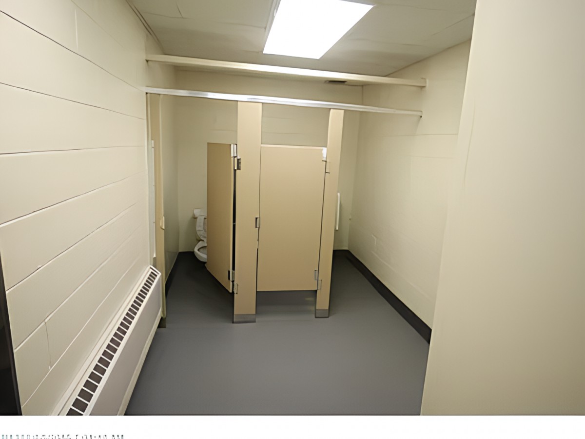 An empty public restroom with a single toilet stall.