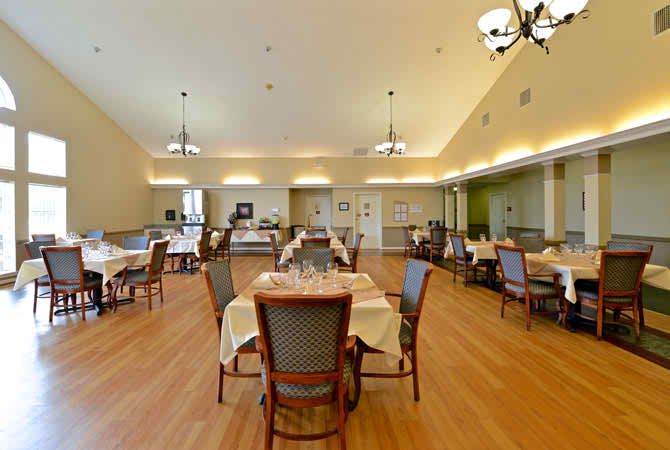 A spacious dining room with elegantly set tables and stylish chandeliers.