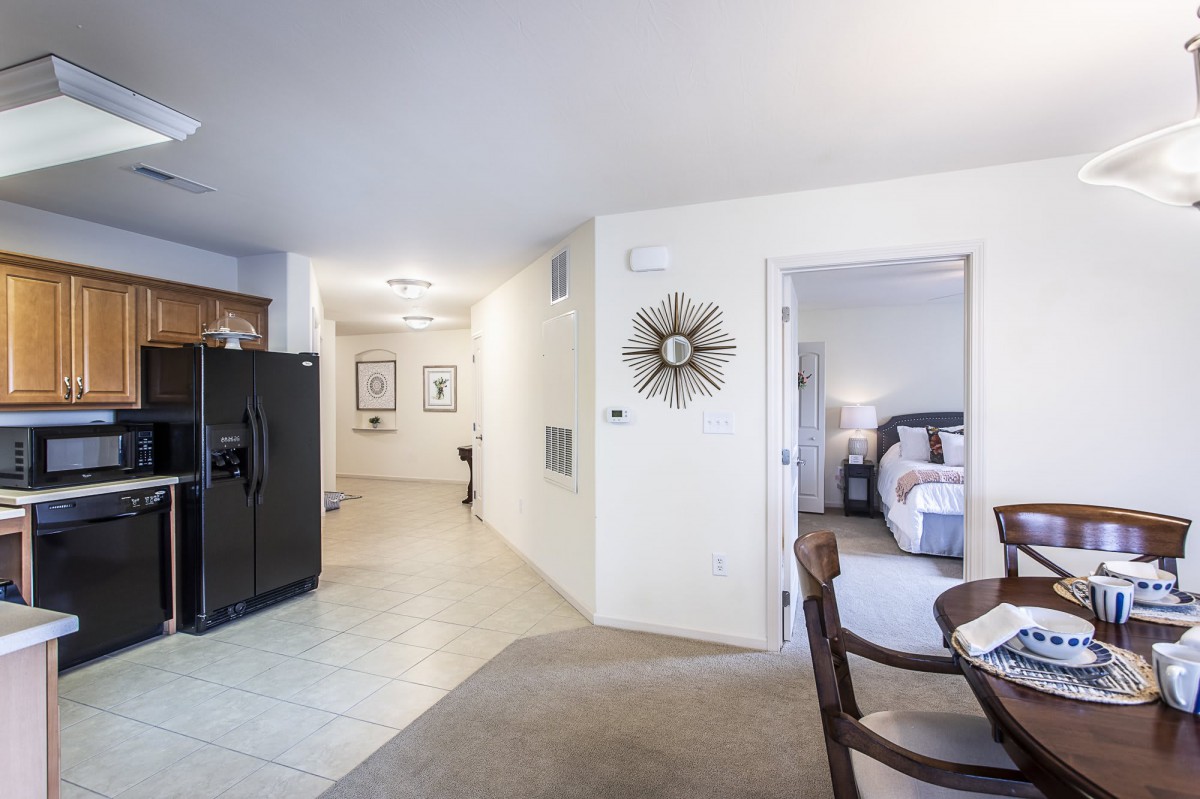 A modern apartment interior featuring an open layout with a view of both the kitchen and bedroom.