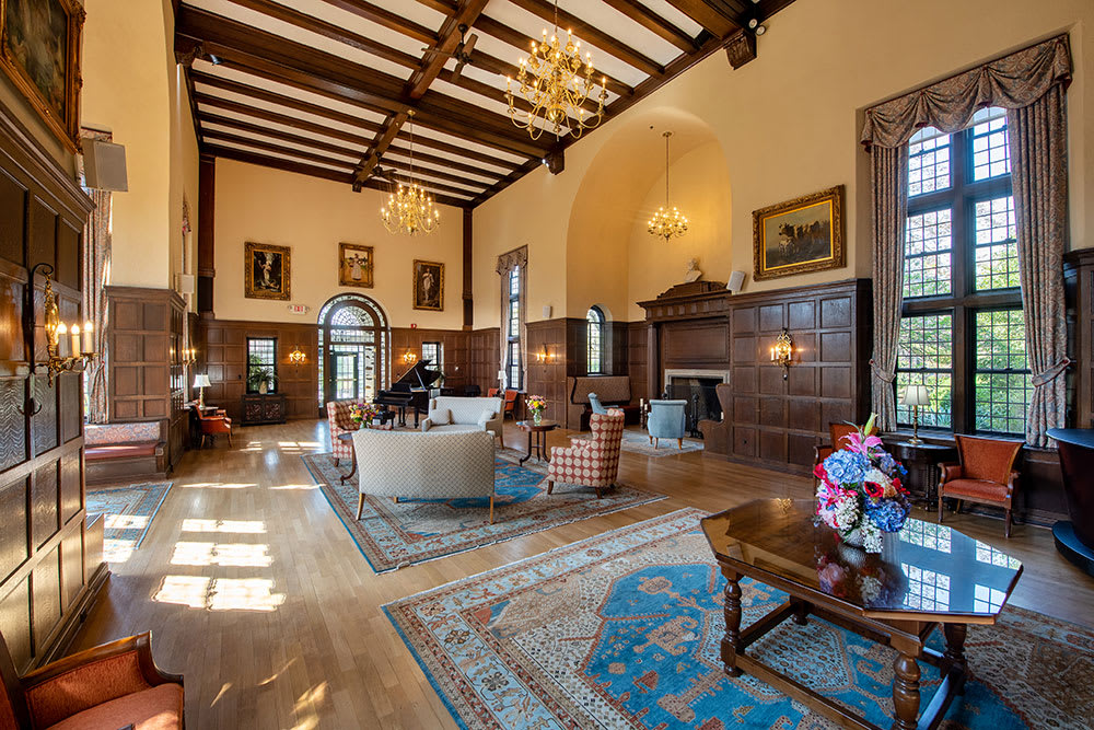 A luxurious and elegant living room with high ceilings, wooden beams, chandeliers, and classic furniture.