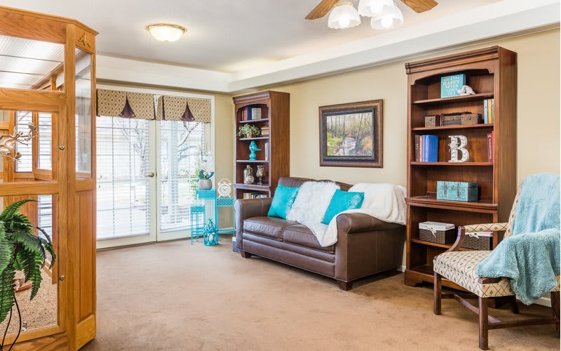 A cozy living room with a comfortable sofa, surrounded by bookshelves and tasteful decor.