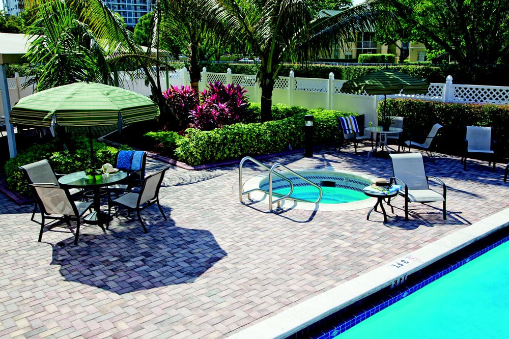 A serene outdoor patio area with a pool and hot tub, surrounded by lush greenery and comfortable seating.