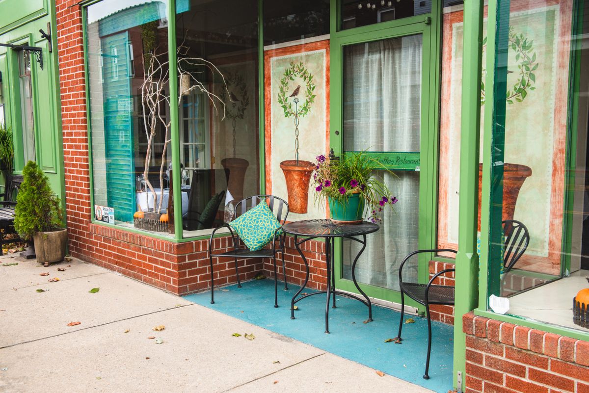 Charming cafe storefront with green accents and outdoor seating.