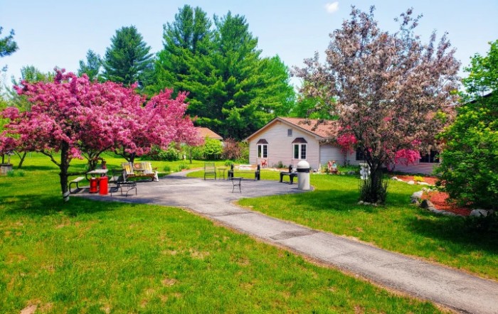 A quaint house surrounded by blooming trees and a lush garden in spring.