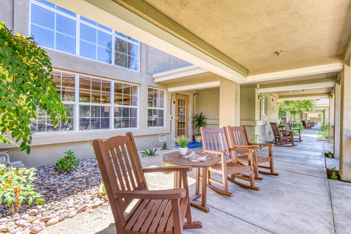 A cozy outdoor patio with wooden rocking chairs and tables, perfect for relaxation.