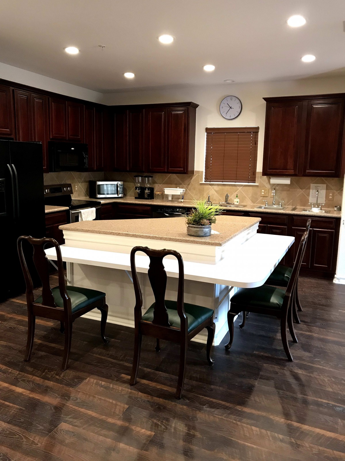 A modern kitchen with dark wood cabinets and a central island featuring dining chairs.