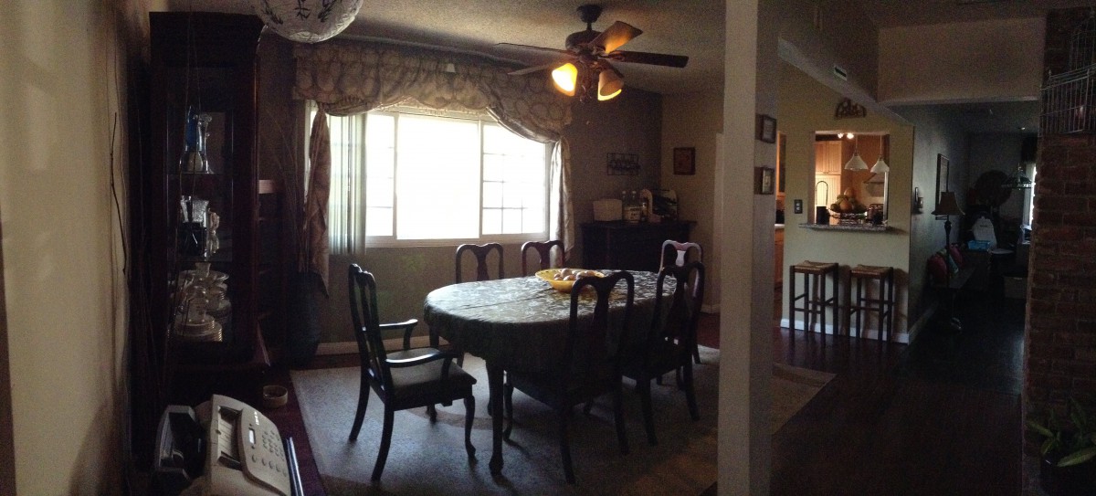 A cozy dining room with a table and chairs, illuminated by a ceiling fan light.