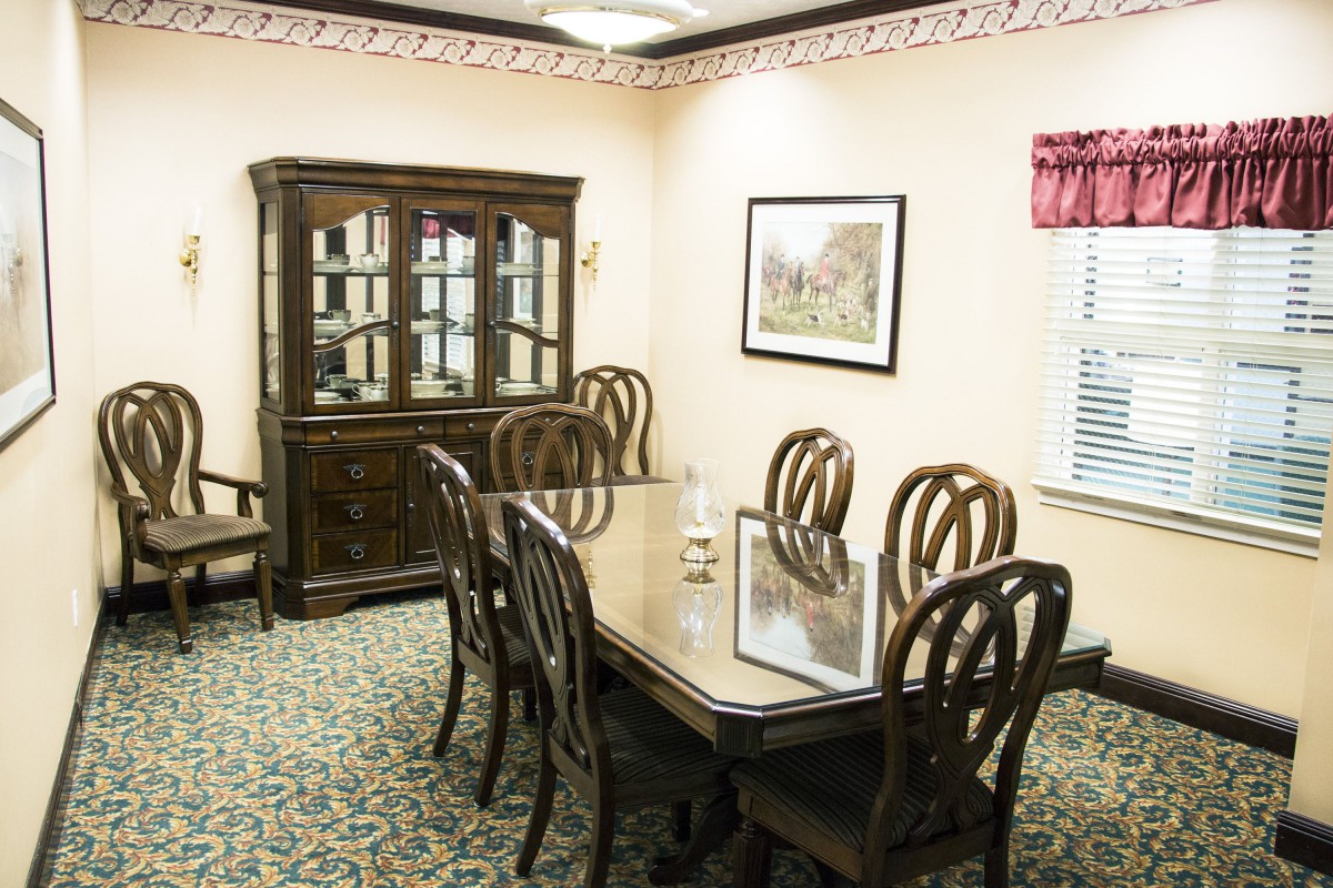 A dining room with a wooden table and chairs, along with a display cabinet and wall decor.