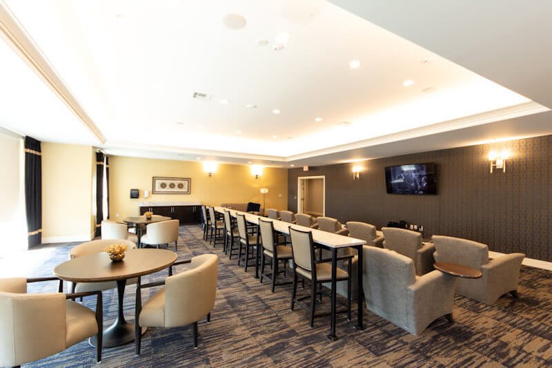 A modern conference room with rows of seating, tables, and a wall-mounted TV screen.