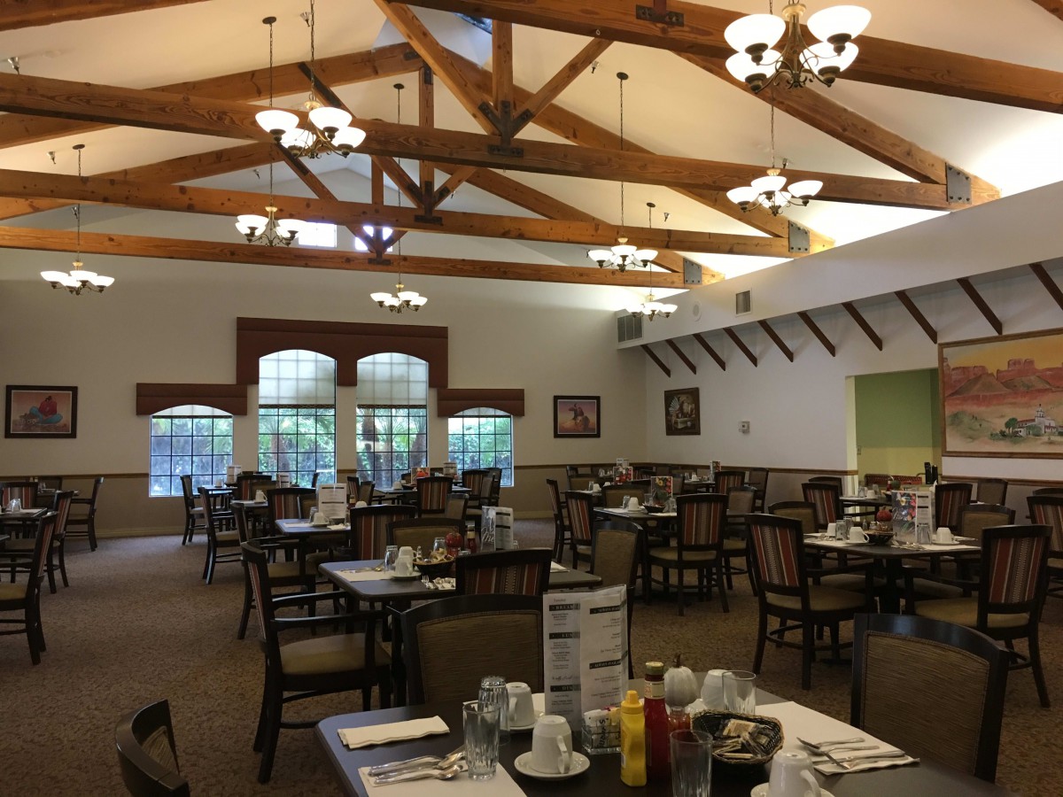 A spacious restaurant dining area with wooden beams and neatly arranged tables.