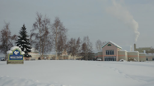 A serene winter landscape featuring a house surrounded by snow-covered ground and bare trees.