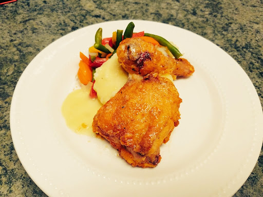 Deliciously plated chicken with a side of vegetables and creamy mashed potatoes.
