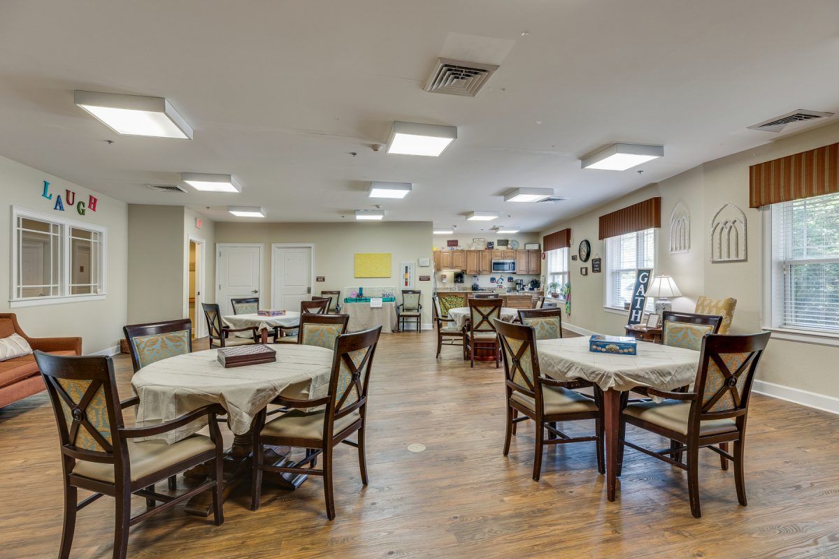 A spacious dining area with several tables and chairs arranged under bright ceiling lights.