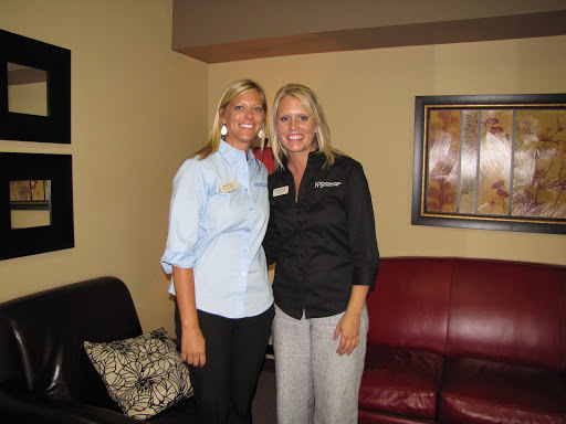 Two smiling women posing together indoors.