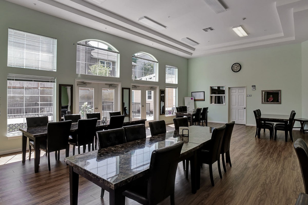 A modern dining room with large windows, wooden floors, and sleek furniture.