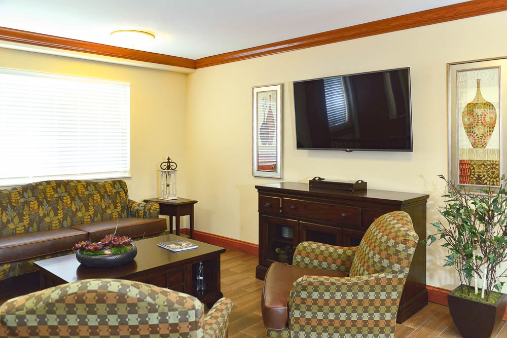 A cozy living room with patterned seating, a flat-screen TV, and wooden furniture.