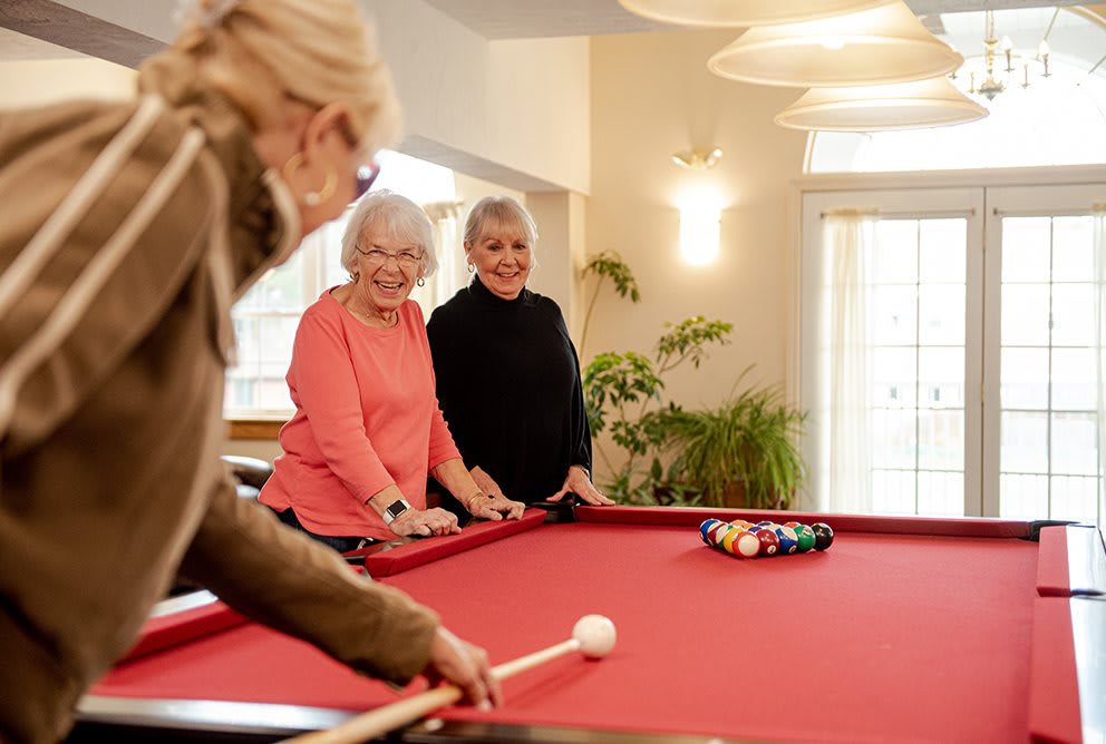 A group of seniors enjoy a friendly game of billiards indoors.