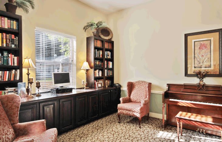 A cozy office space with a desk, armchairs, and a bookshelf.