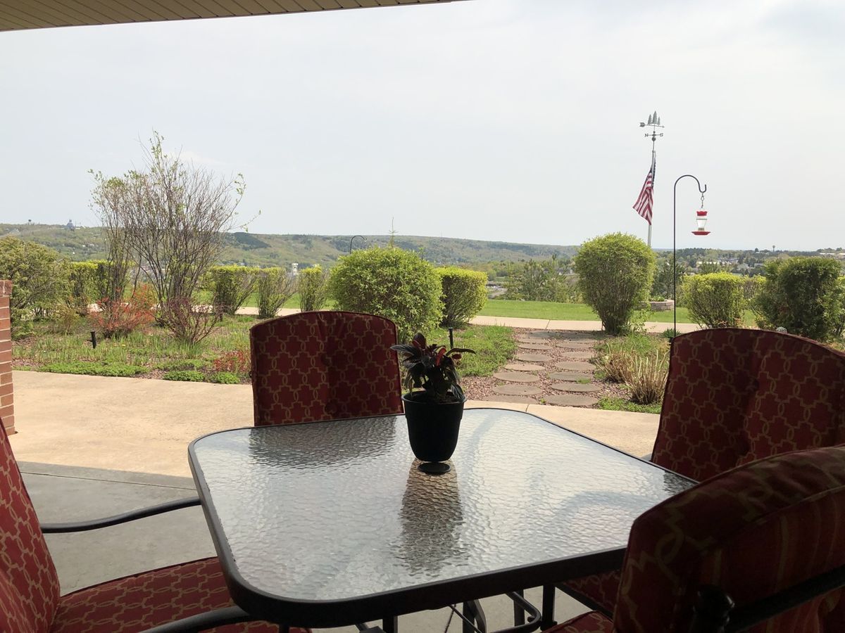 A tranquil patio view overlooking a landscaped garden and open landscape.